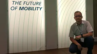 Mężczyzna na tle plakatu z napisem The Future of Mobility